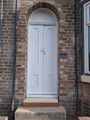A white double door with a small step leading up to it, set in a brick wall with a sign reading "Alice House". - Luxurious 4-bed House With Sauna & Jacuzzi in Sunderland (Sunderland)