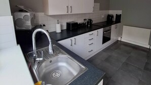 Une cuisine moderne avec des meubles blancs, un évier en acier inoxydable et un plan de travail noir.