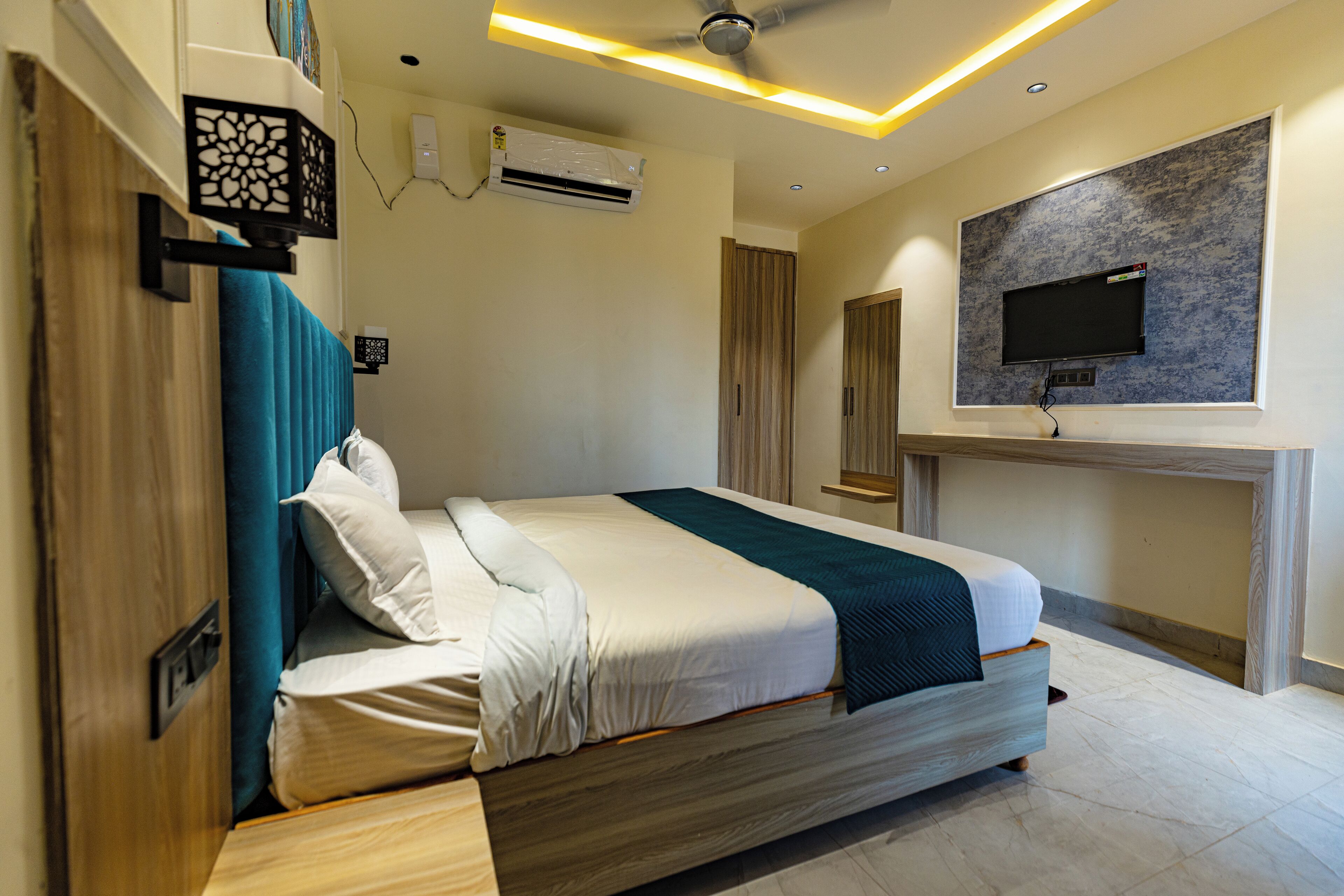 A modern bedroom with a bed, a mounted TV, and an air conditioning unit.