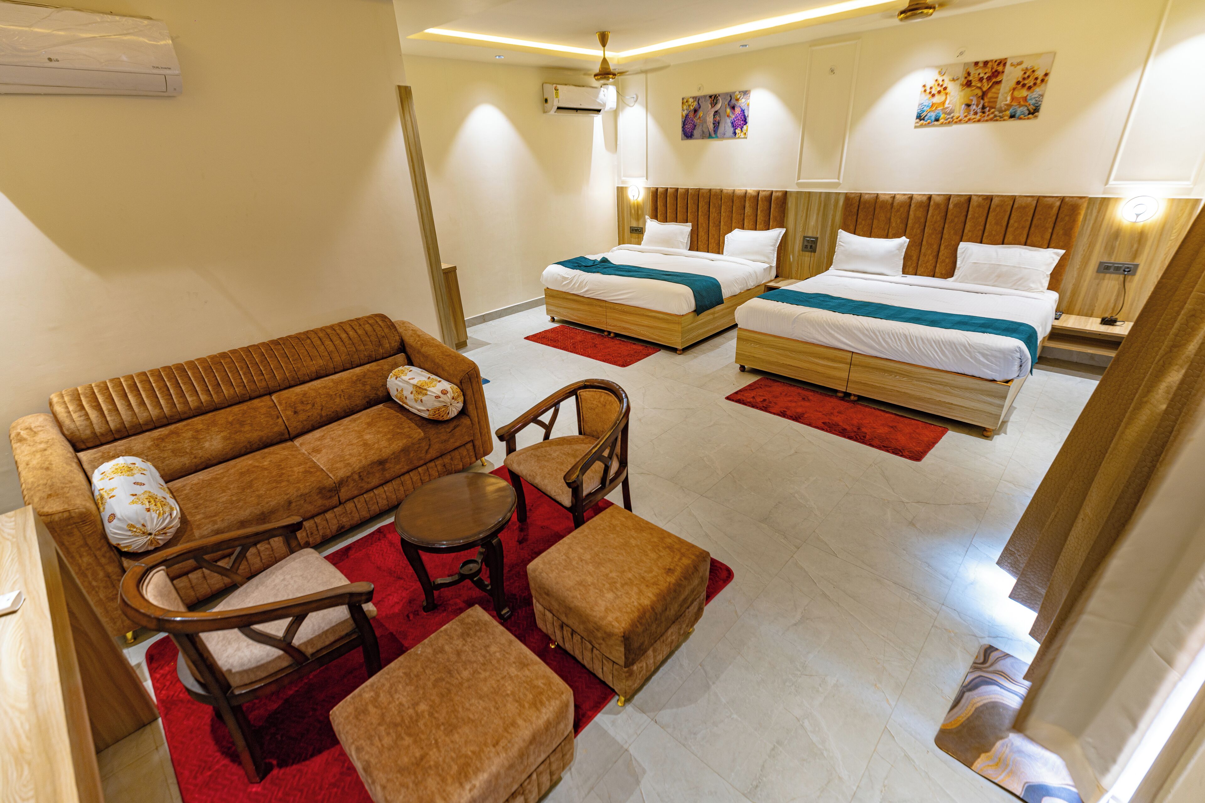 A hotel room with a sofa, two single beds, a small table, and a chair.
