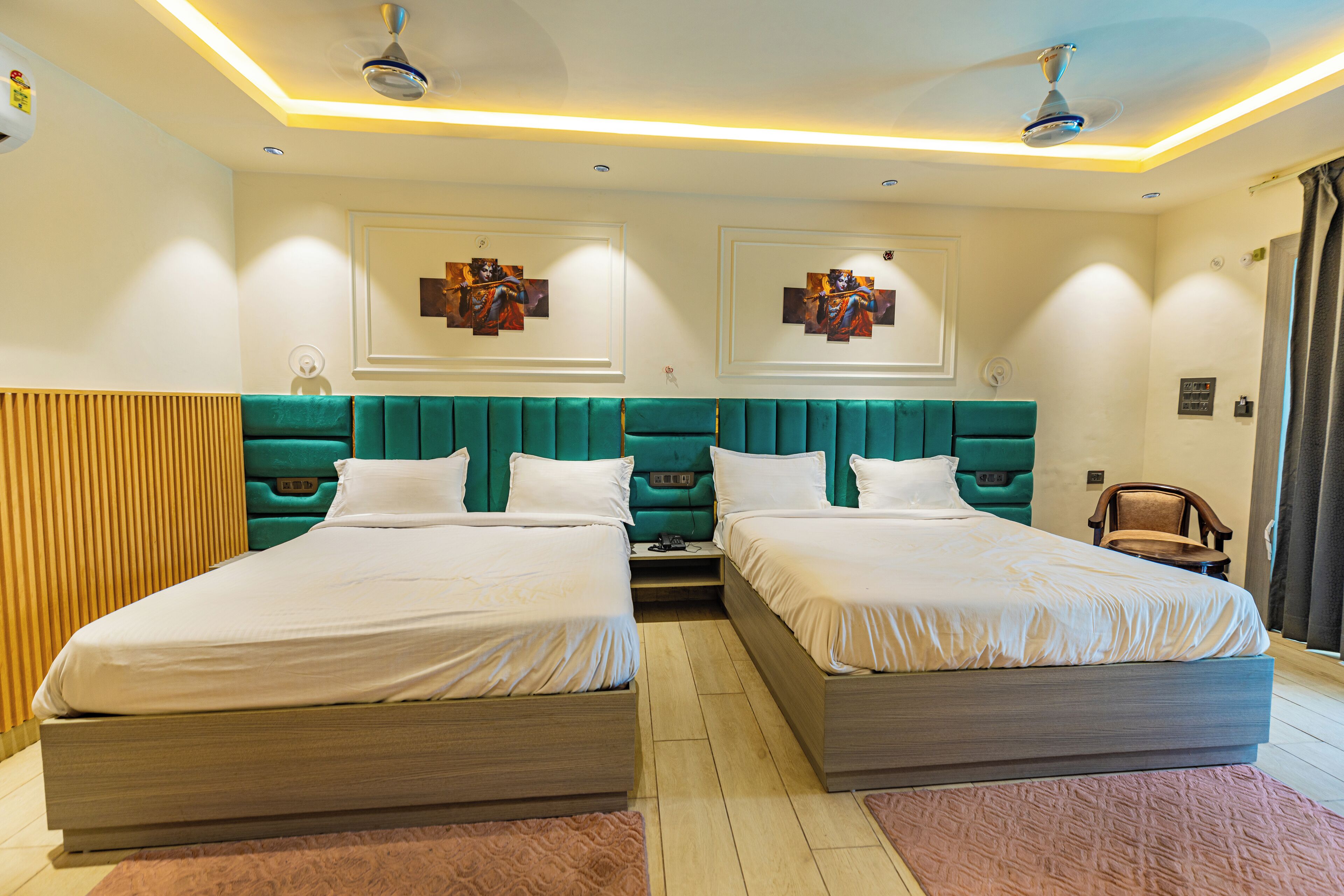 A hotel room with two beds, a wooden headboard, a ceiling fan, and artwork on the walls.