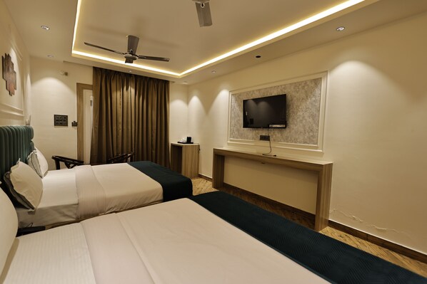 A hotel room with two beds, a ceiling fan, a flat-screen TV mounted on the wall, and a wooden nightstand.