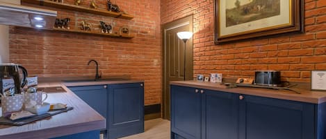 A kitchen with brick walls, wooden ceiling, and a framed painting.