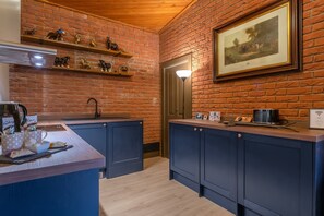 A kitchen with brick walls, wooden ceiling, and a framed painting. - Pools Cottage 14-Stable House Warwickshire Escape (Kenilworth)