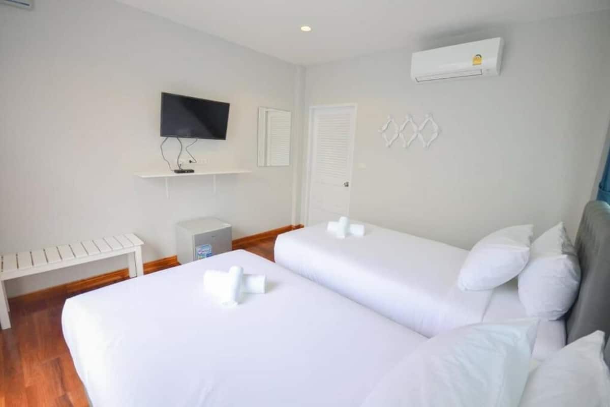 Une chambre d’hôtel avec deux lits, une télévision, un climatiseur et un banc.