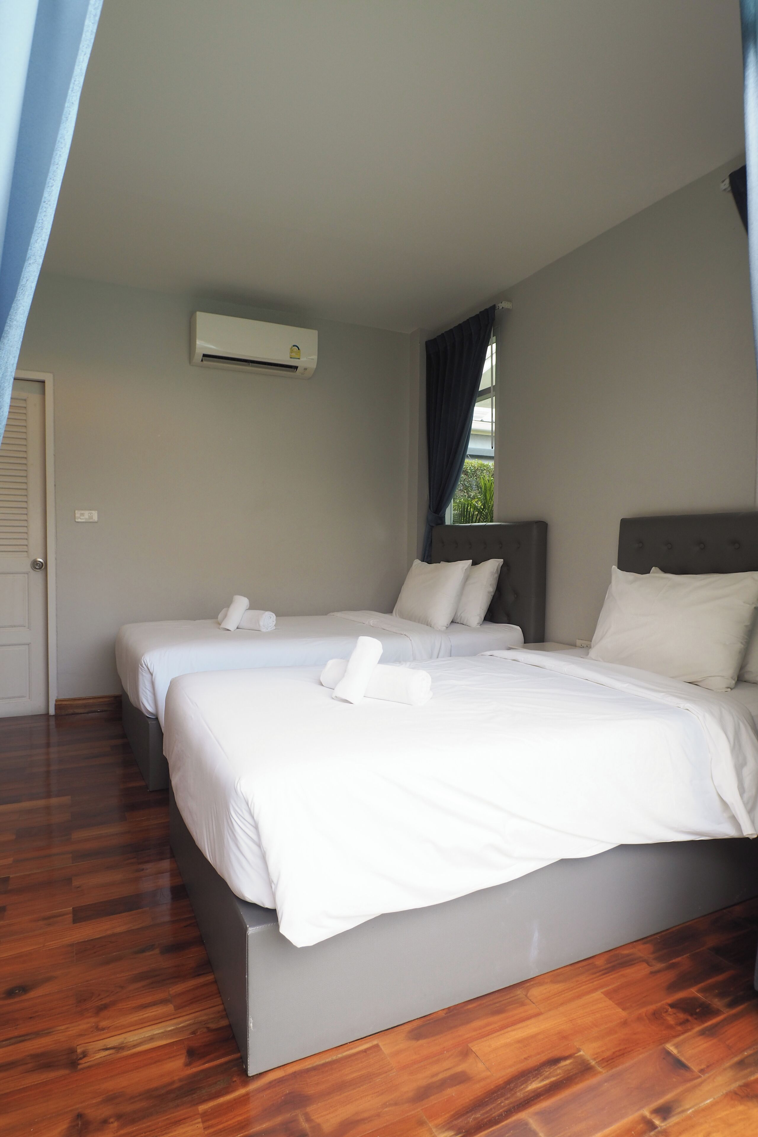 Ein Hotelzimmer mit zwei Betten, einem Deckenventilator und einer Klimaanlage.