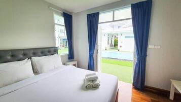 Une chambre d’hôtel avec un lit, une table de chevet et une vue sur une piscine.
