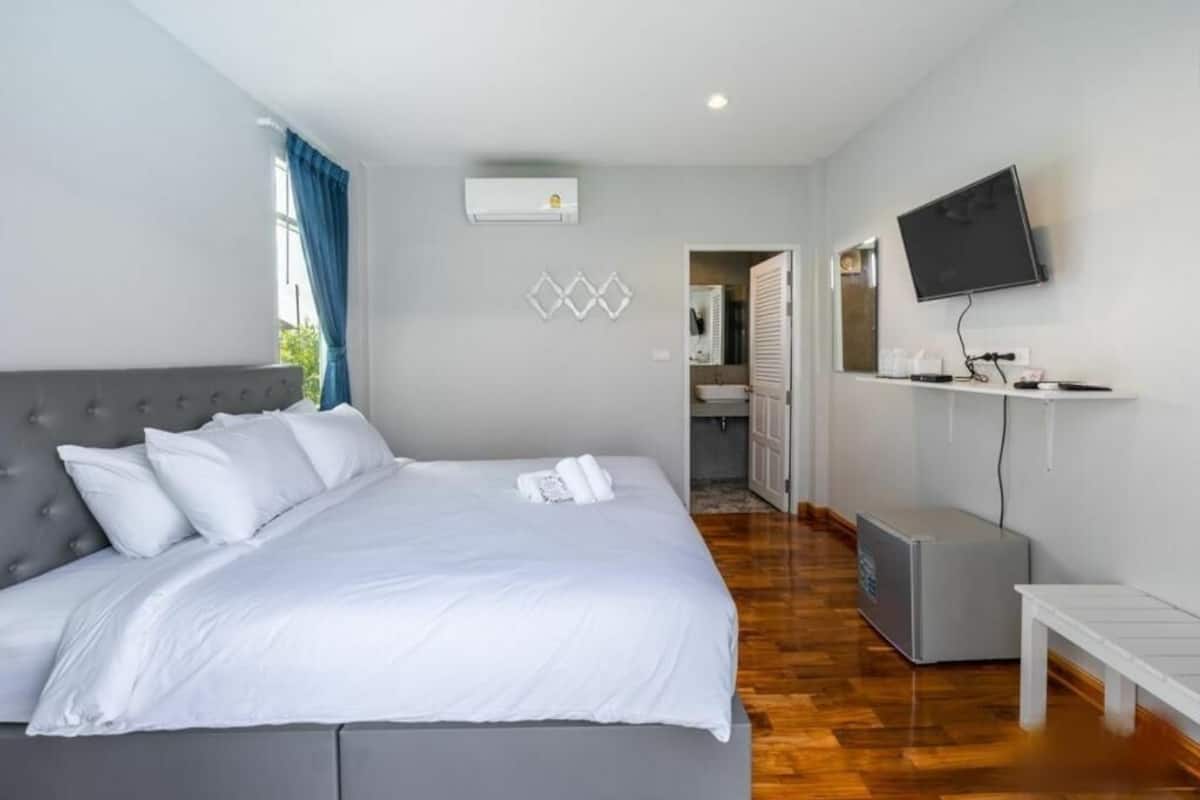 Une chambre avec un lit, une télévision, un climatiseur et une petite table.