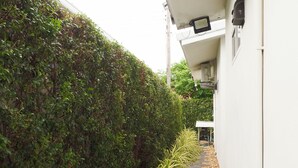 A narrow pathway with stepping stones, flanked by a neatly trimmed hedge and potted plants. - Bianco House (Cha-am)