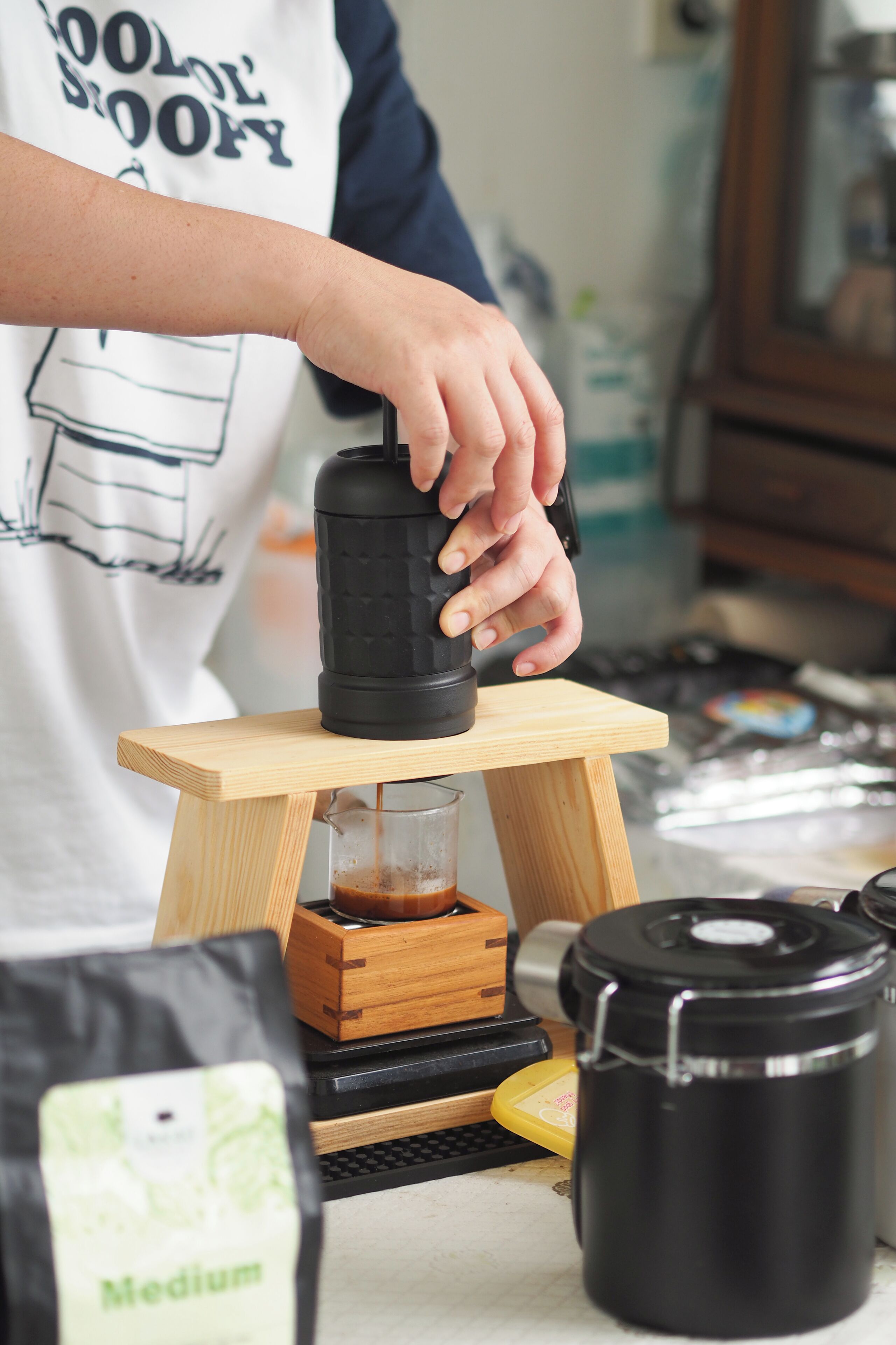 Une personne utilise un moulin à café posé sur un support en bois.