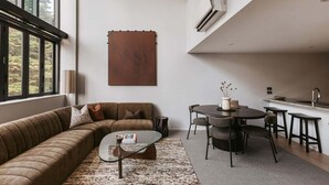 A modern living room with a sofa, coffee table, and dining area. - Tree Tops Loft - Stylish, Private 2-Bedroom Retreat in Mount Maunganui (Mount Maunganui)