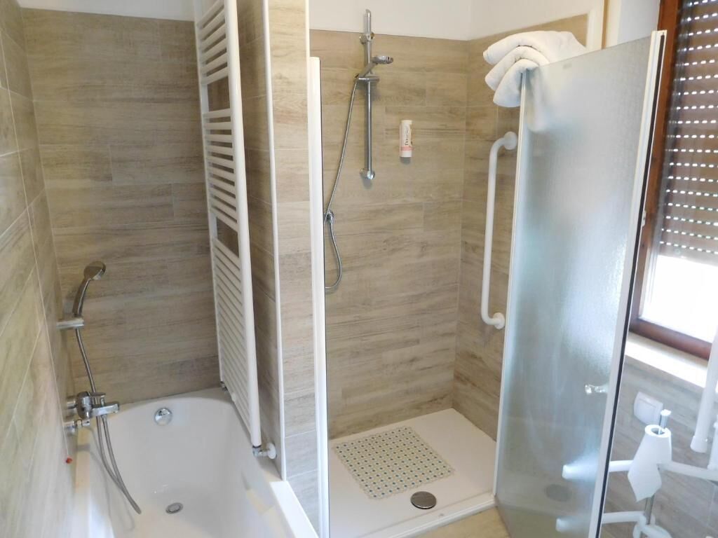 A modern bathroom with a glass shower enclosure, a separate bathtub, and a toilet.