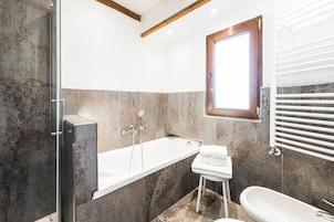 Un baño moderno con una bañera grande, ducha e inodoro.