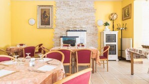 A dining area with tables set for four, a fireplace, and a clock on the wall. - Hotel Vescovi (Asiago)
