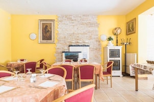 Un comedor con mesas dispuestas para cuatro personas, una chimenea y un reloj en la pared.