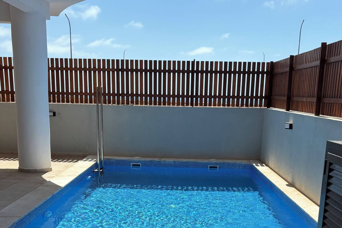 Una piscina amb terrassa de fusta, gandules i un autèntic racó de relaxació amb begudes i un barret.