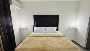 A bedroom with a bed, two bedside tables, a ceiling fan, and an air conditioning unit. - Modern Luxury Condo With Pool Access in Kingston, Jamaica (Kingston)
