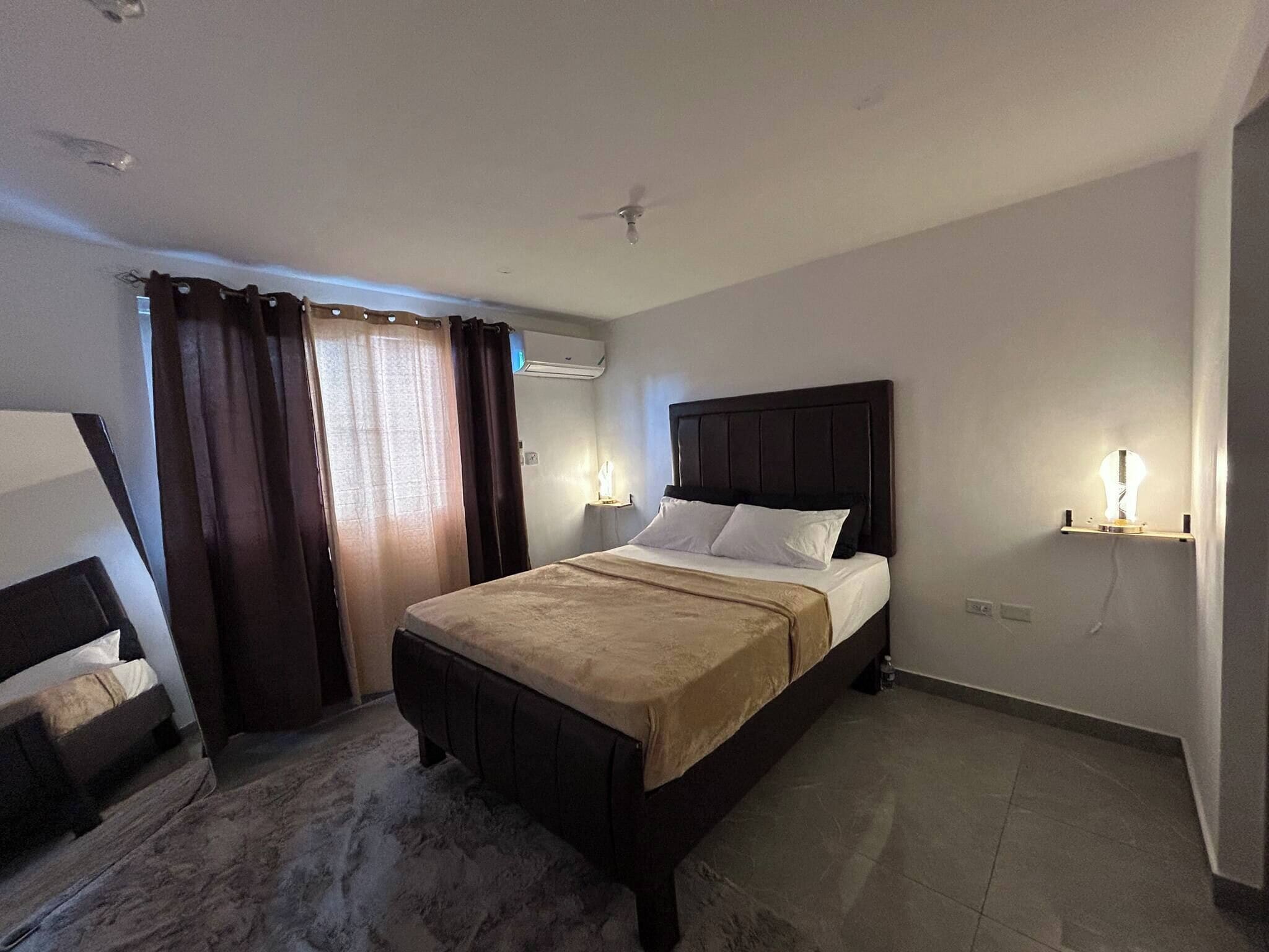 Ein Hotelzimmer mit Bett, Schreibtisch, Stuhl und einem fenster mit Vorhängen.