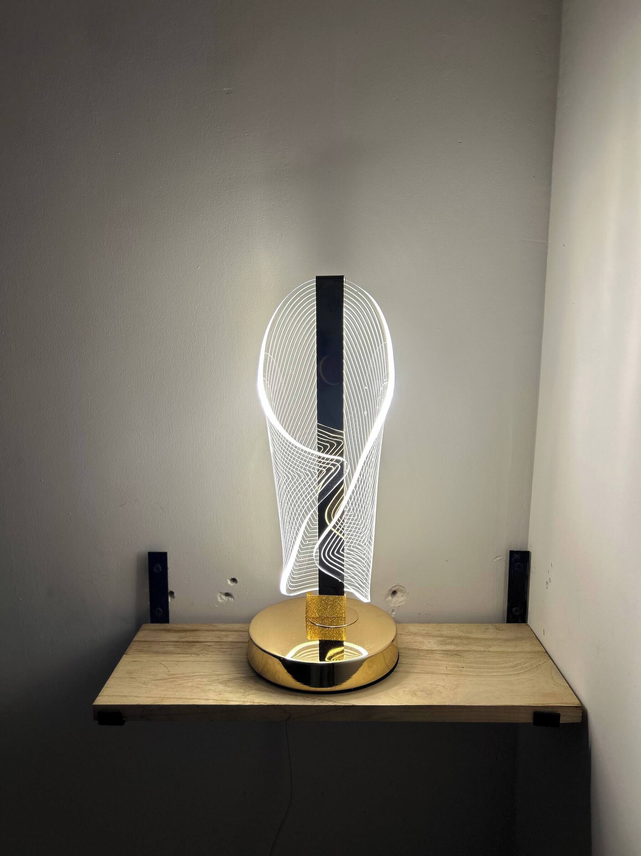 Una lámpara de mesa moderna con un diseño geométrico sobre una mesa de madera frente a una pared lisa.