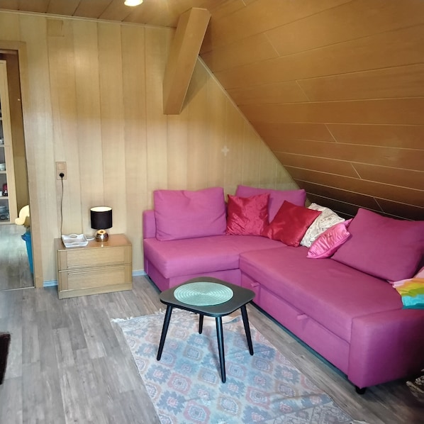 A cozy living room with a pink sofa, a small table, and a lamp.