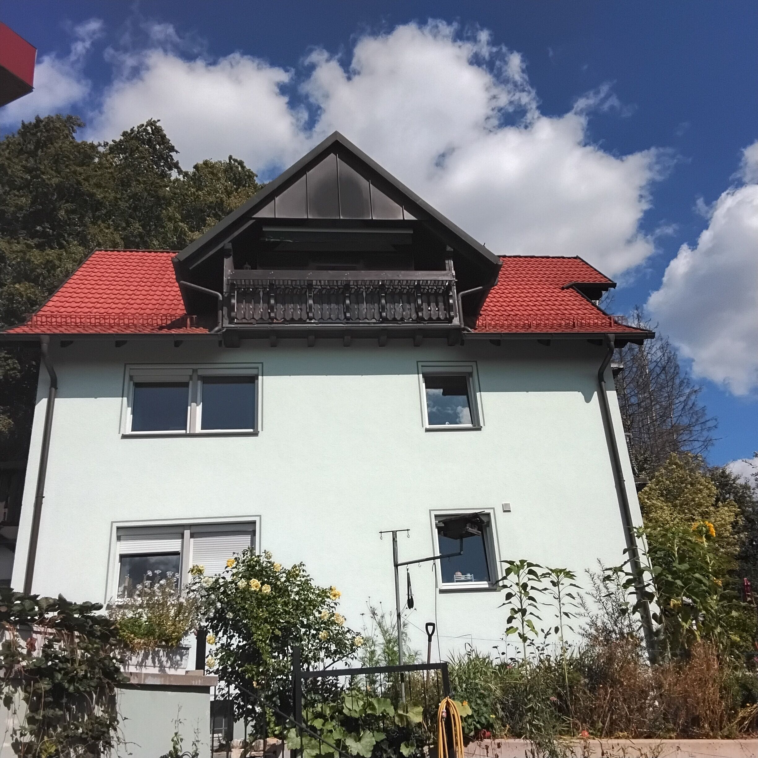 A two-story building with a red roof, multiple windows, and a balcony.