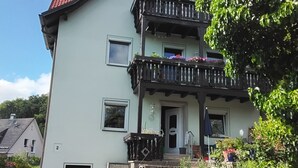 A two-story building with a balcony, a door, and a small window.