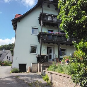 A two-story building with a balcony, a door, and a small window.