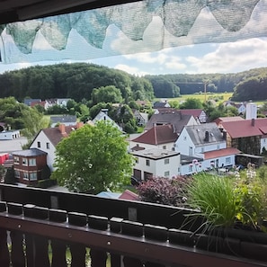 A residential area with houses, a large tree, and a view of the countryside.