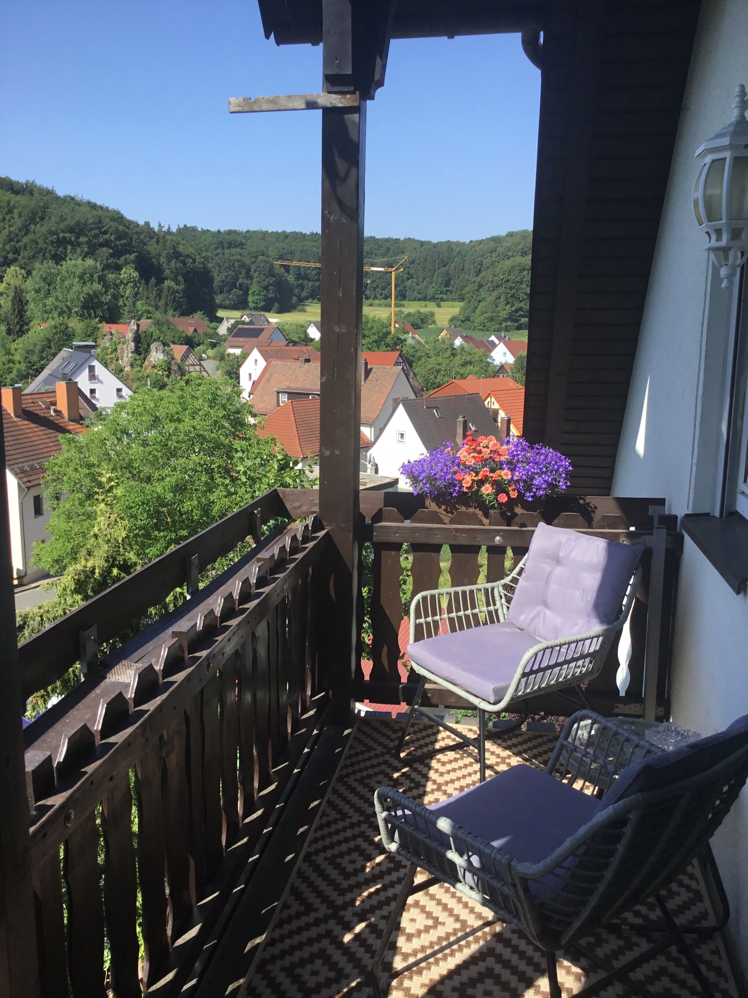 Un balcone con una sedia, un tavolo e un vaso di fiori.