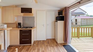 Een kleine keuken met houten kastjes, een magnetron en een koffiezetapparaat.