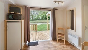 Een kamer met een houten vloer, een witte radiator, een televisie op een plank, een stoel en een grote spiegel aan de muur.