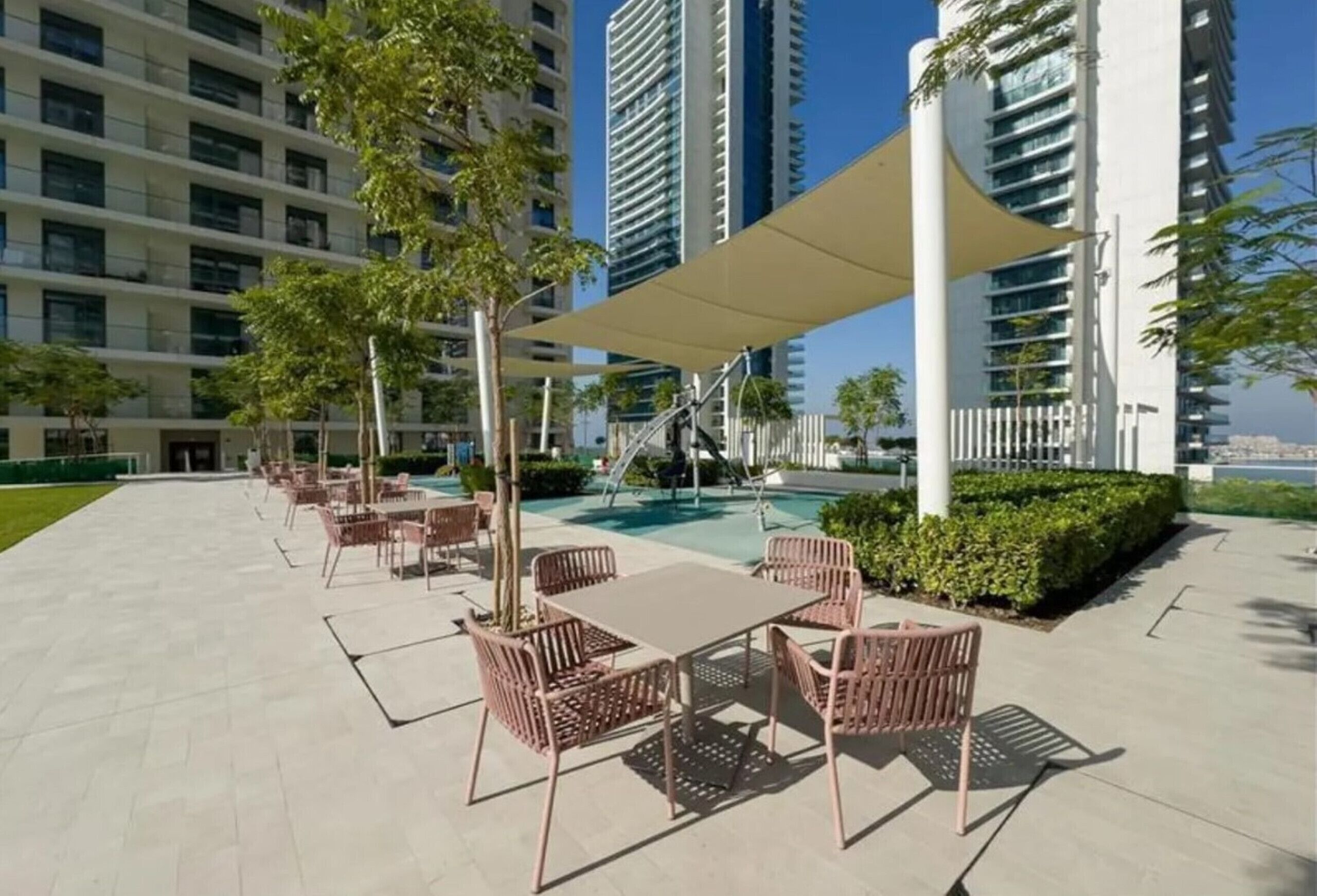 Una terraza en la azotea con mobiliario exterior, una piscina y rascacielos al fondo.