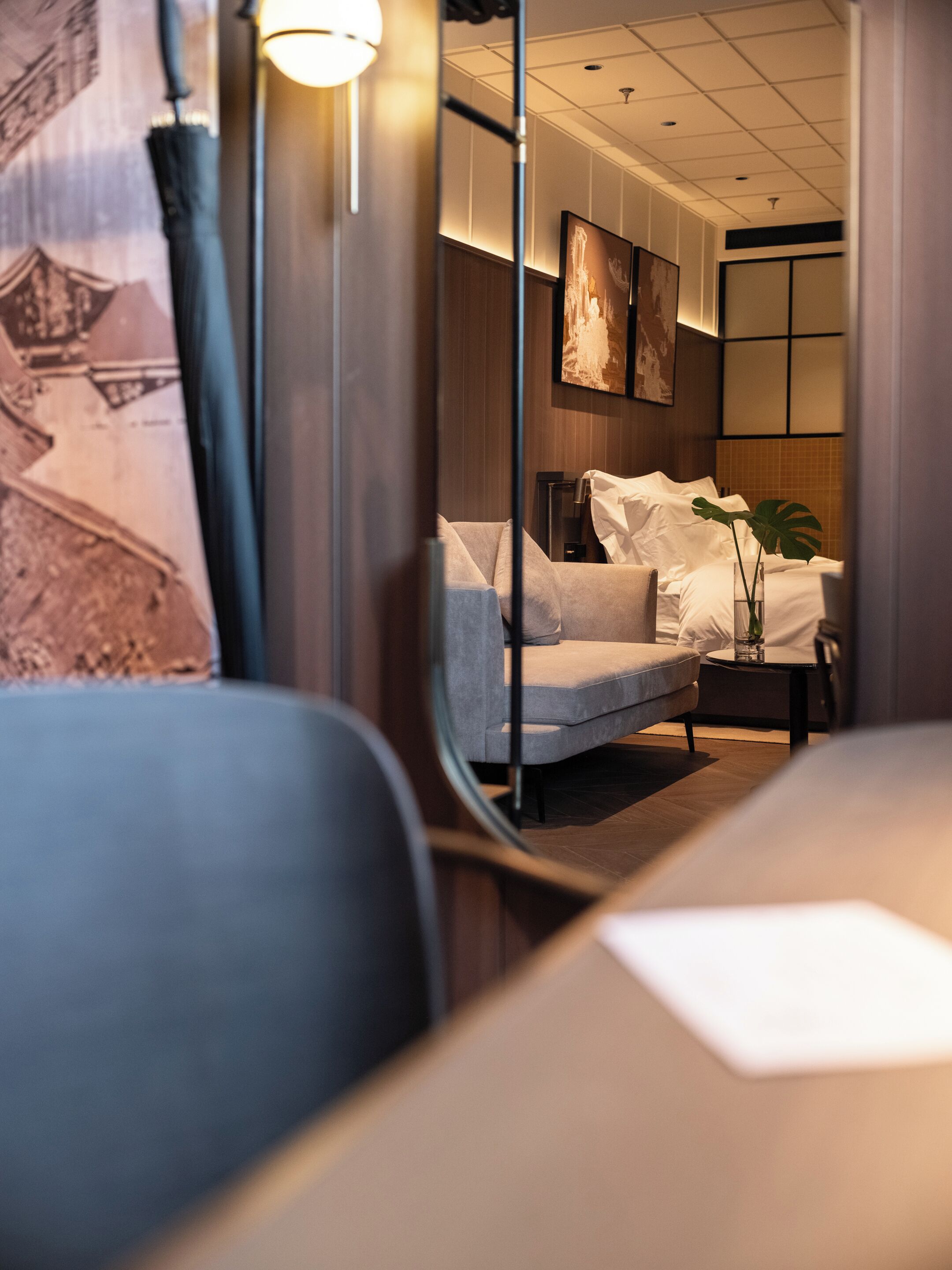 Una habitación de hotel con un sofá, una mesita y una planta.