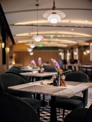 Un restaurant avec des tables, des chaises et des lampes suspendues.