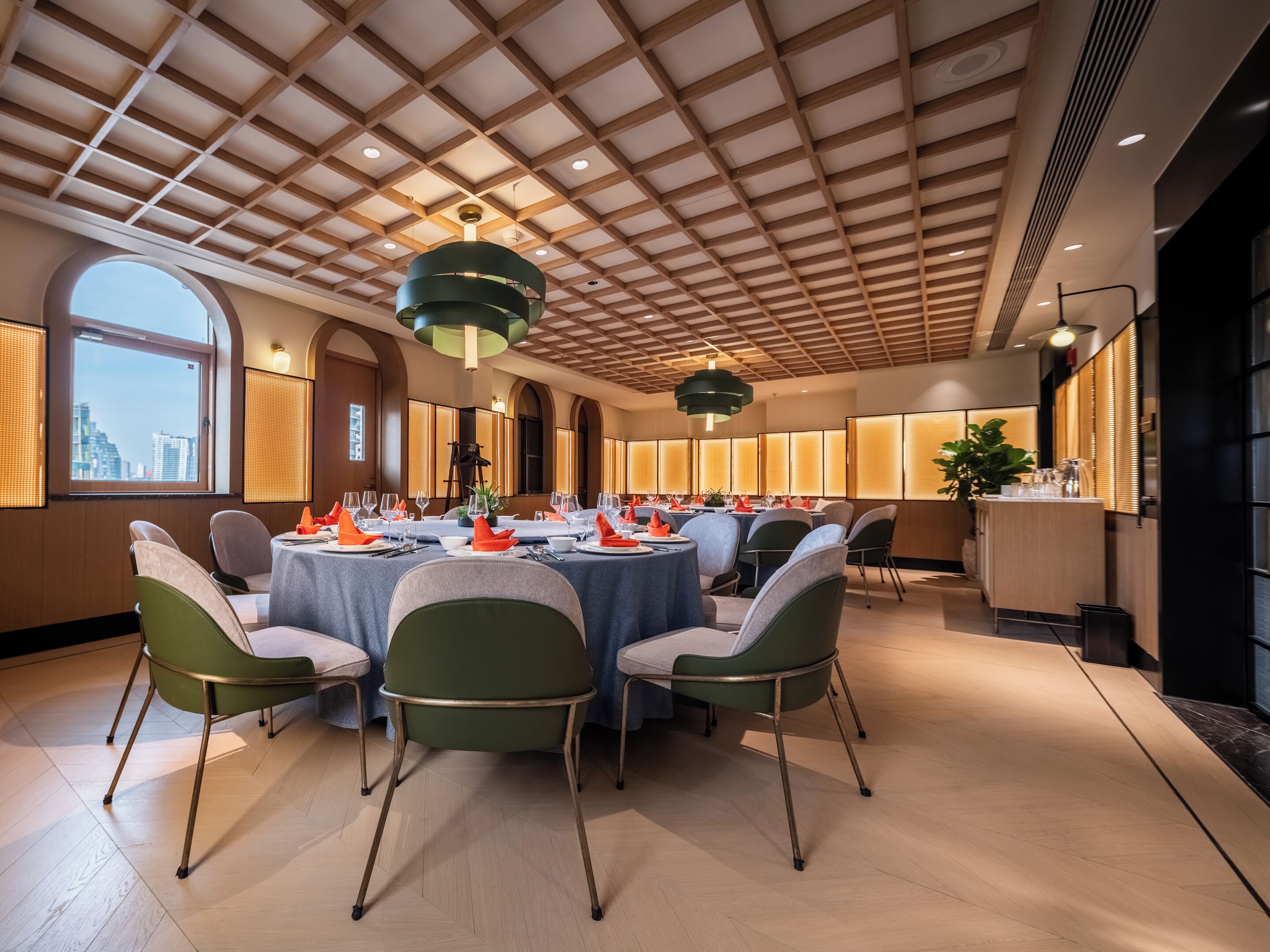 Un espace repas avec des tables rondes, des chaises et une vue sur la ville grâce à de grandes fenêtres.