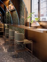 A bar area with metal-framed chairs, a potted plant, and a curved counter.
