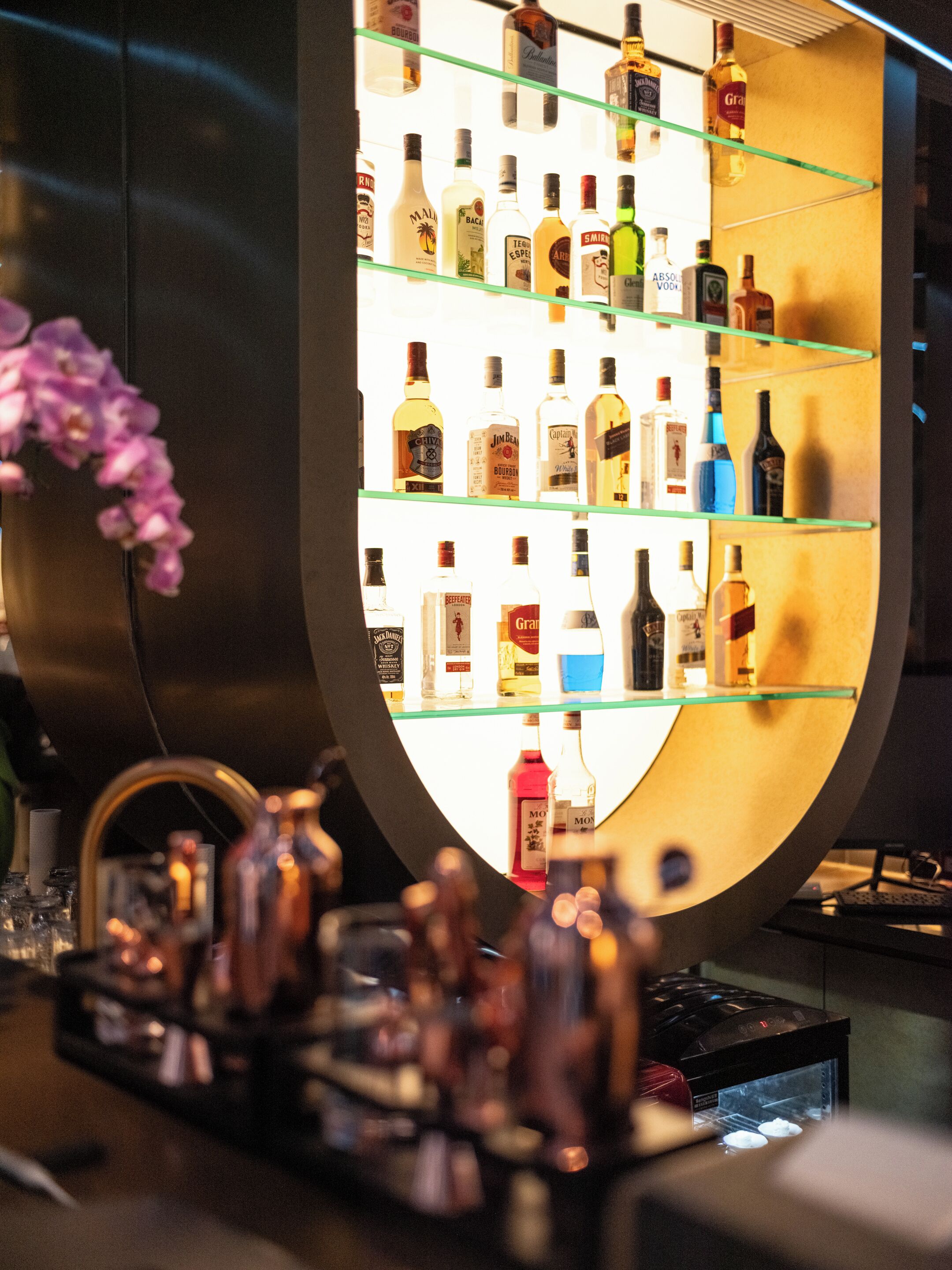 A bar area with shelves of various liquor bottles.