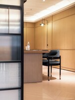A modern reception area with a wooden panel wall, a reception desk, and a black chair.