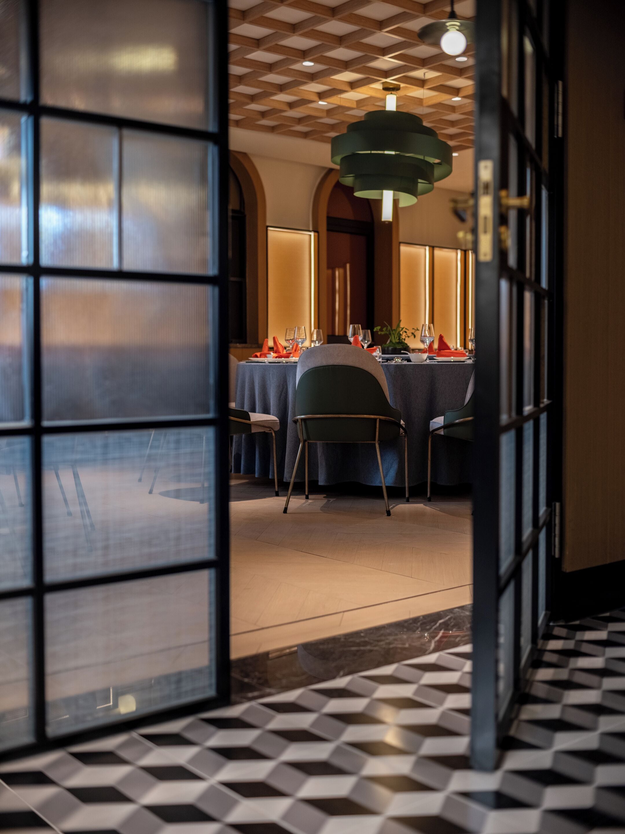 A dining area with a table set for four, a patterned floor, and a modern ceiling design.