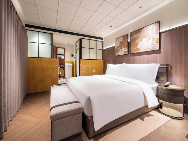 Habitación de hotel con cama, mesita de noche y vista al baño.