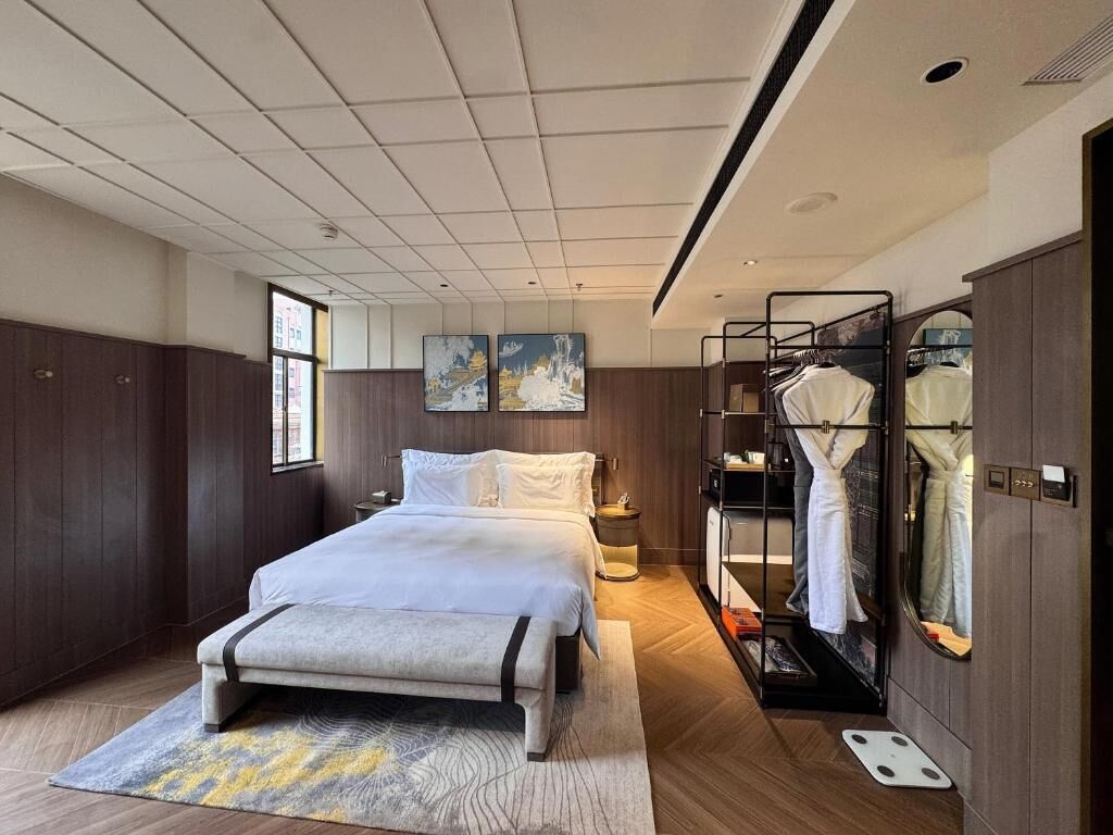 A modern bedroom with a bed, bedside tables, a wardrobe, and a mirror.