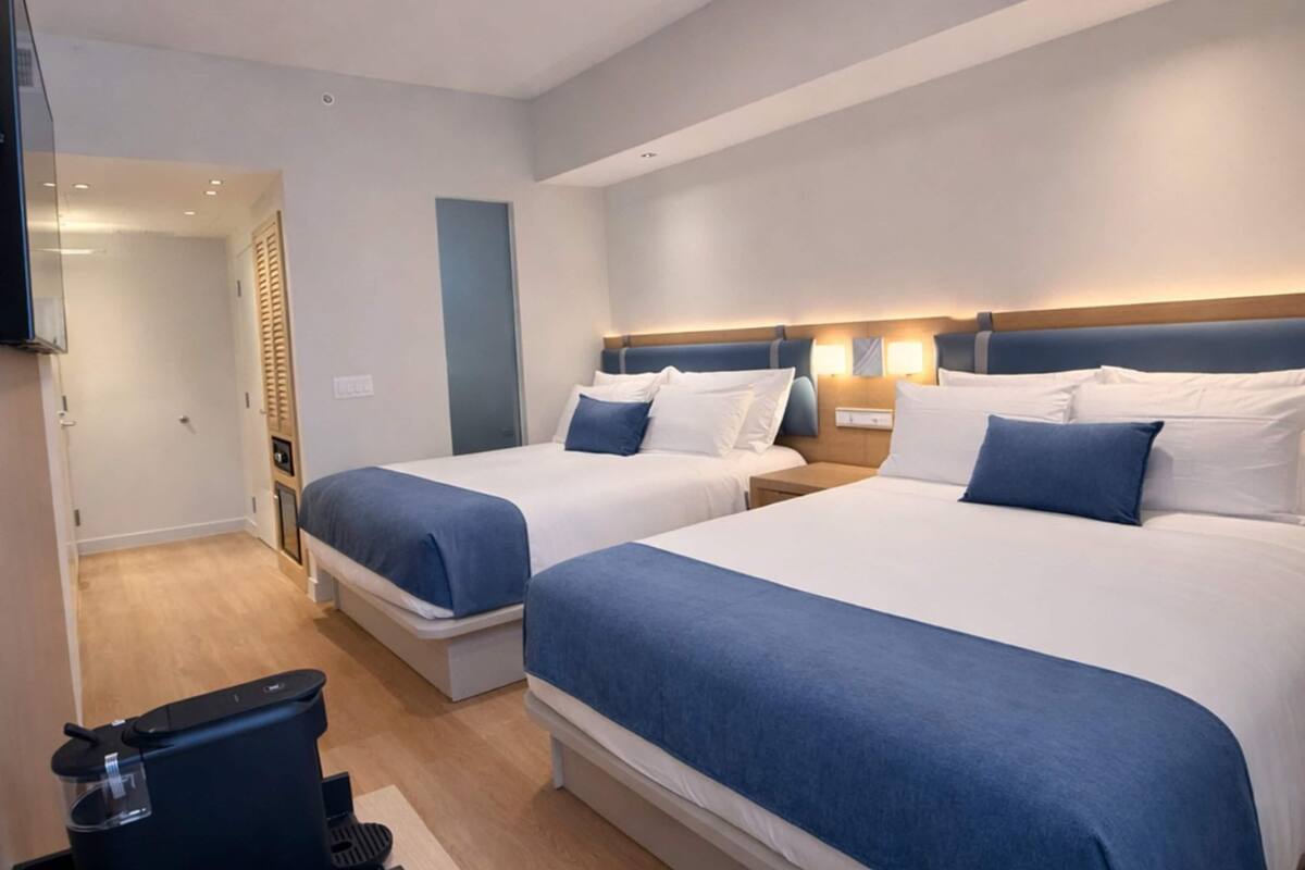 Ein Hotelzimmer mit zwei Betten, einem Fernseher, einem Schreibtisch und einem Sessel.