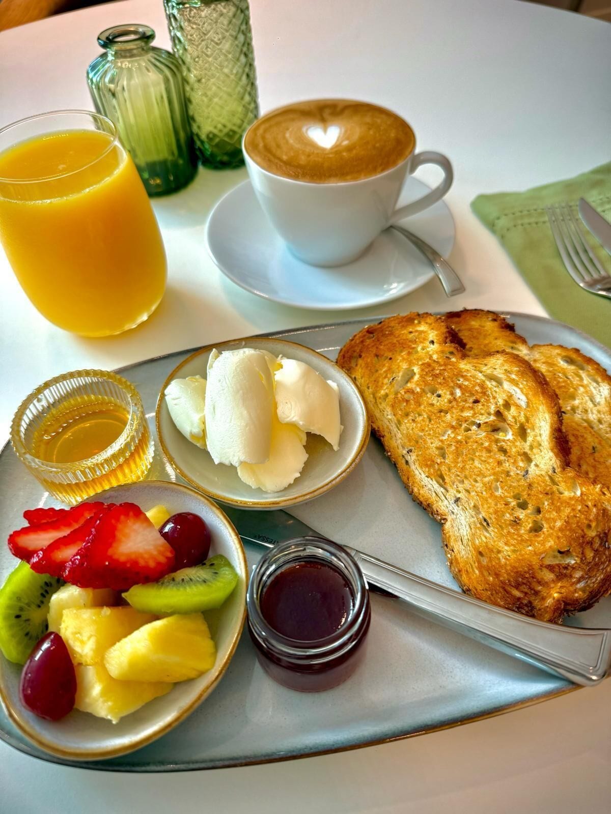 A breakfast tray with toast, fruit, butter, jam, and a cup of coffee.
