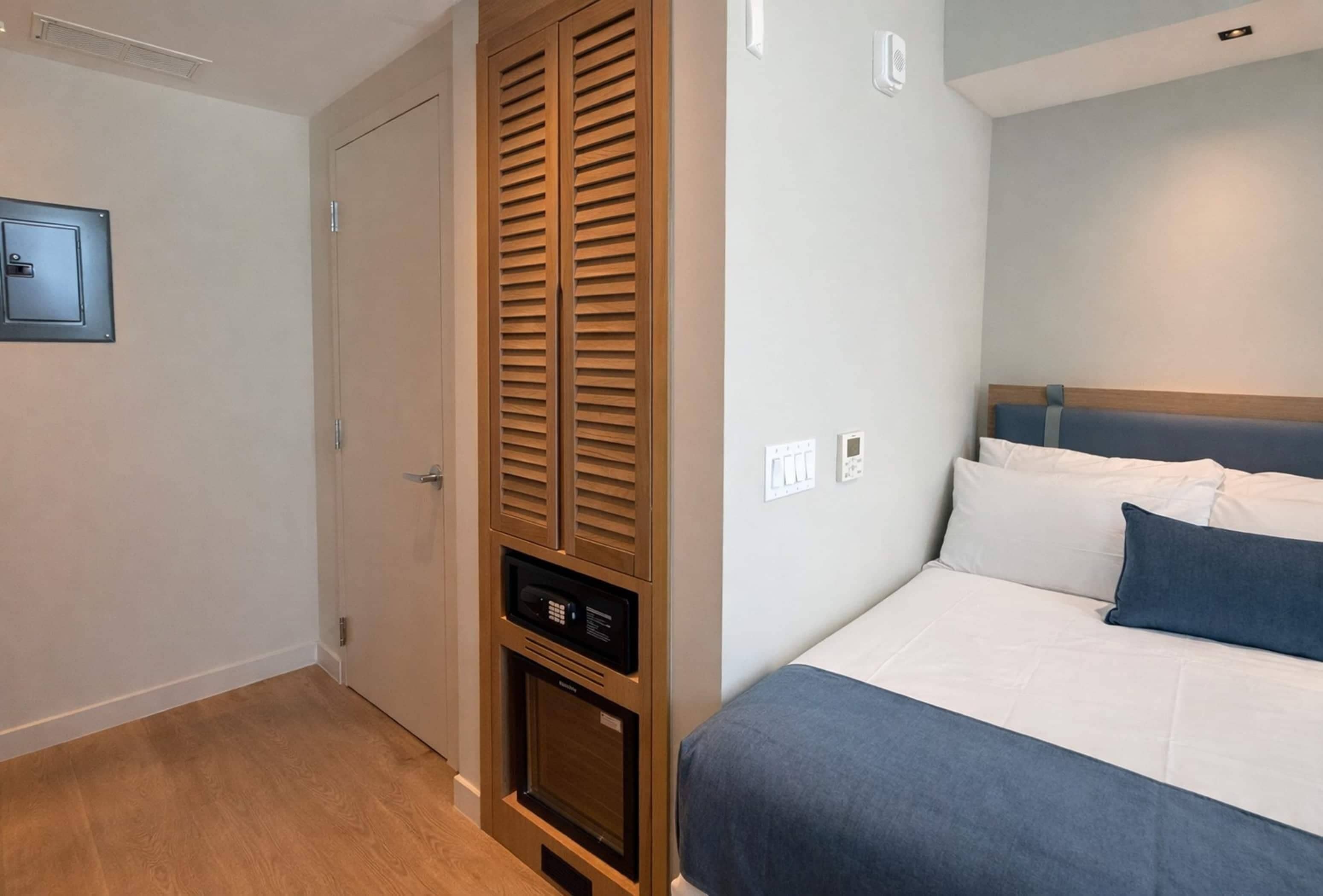 Un dormitorio con cama, armario, calefacción integrada y un interruptor de luz en la pared.