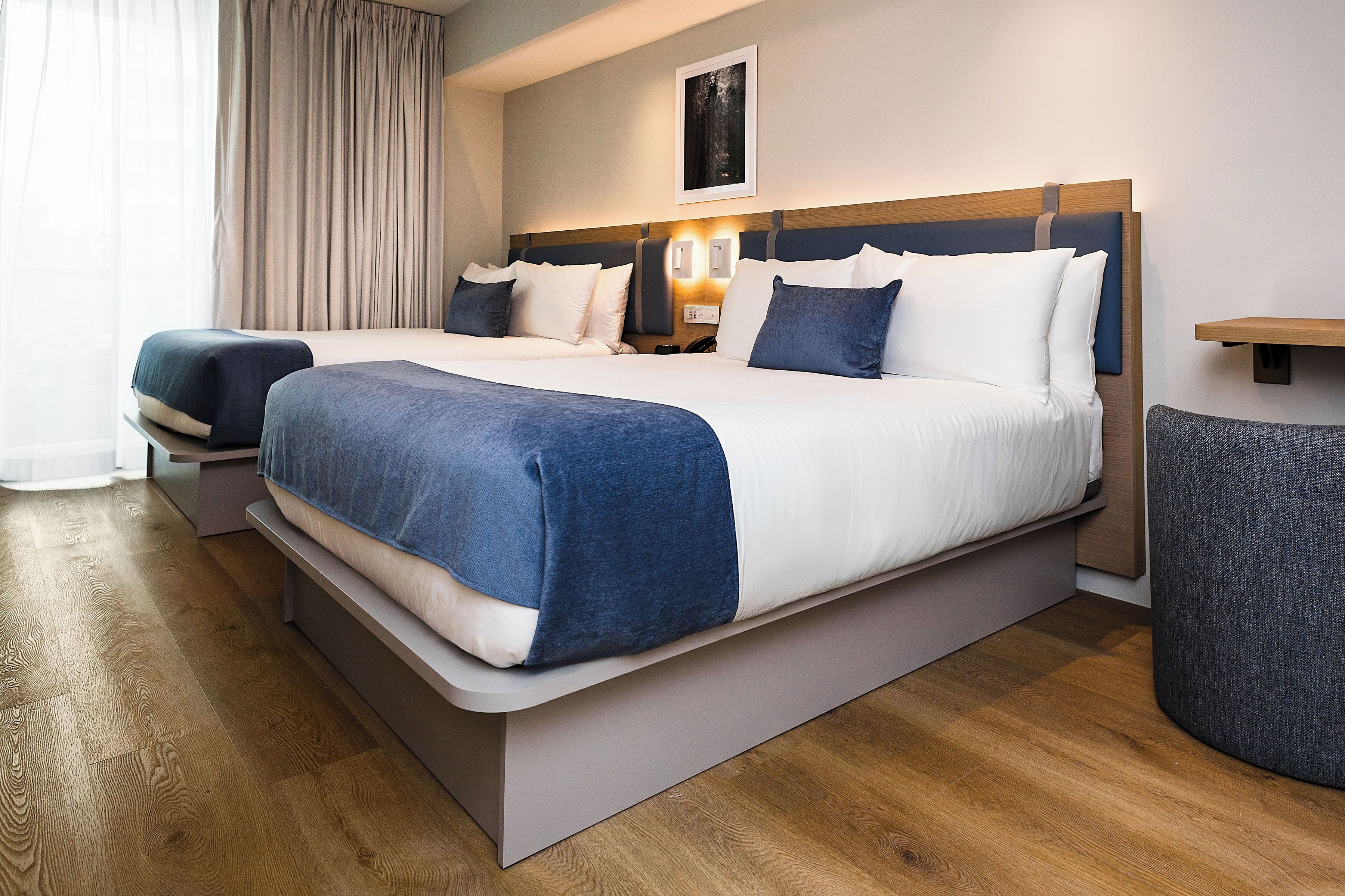 A double bed with a wooden headboard, a bedside table, and a chair.