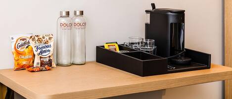 A breakfast bar with snacks, Dolce Dolce water bottles, and a coffee machine.
