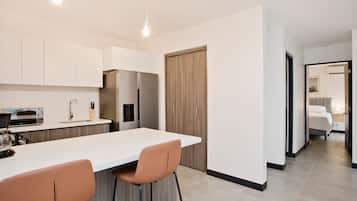 A modern kitchen with a central island, bar stools, a built-in oven, and a refrigerator.