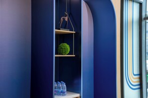 A modern interior with a blue wall, a green decorative object, and water bottles on a shelf. - Holiday Inn Express Suzhou Luzhi Industrial Park by IHG (Suzhou)