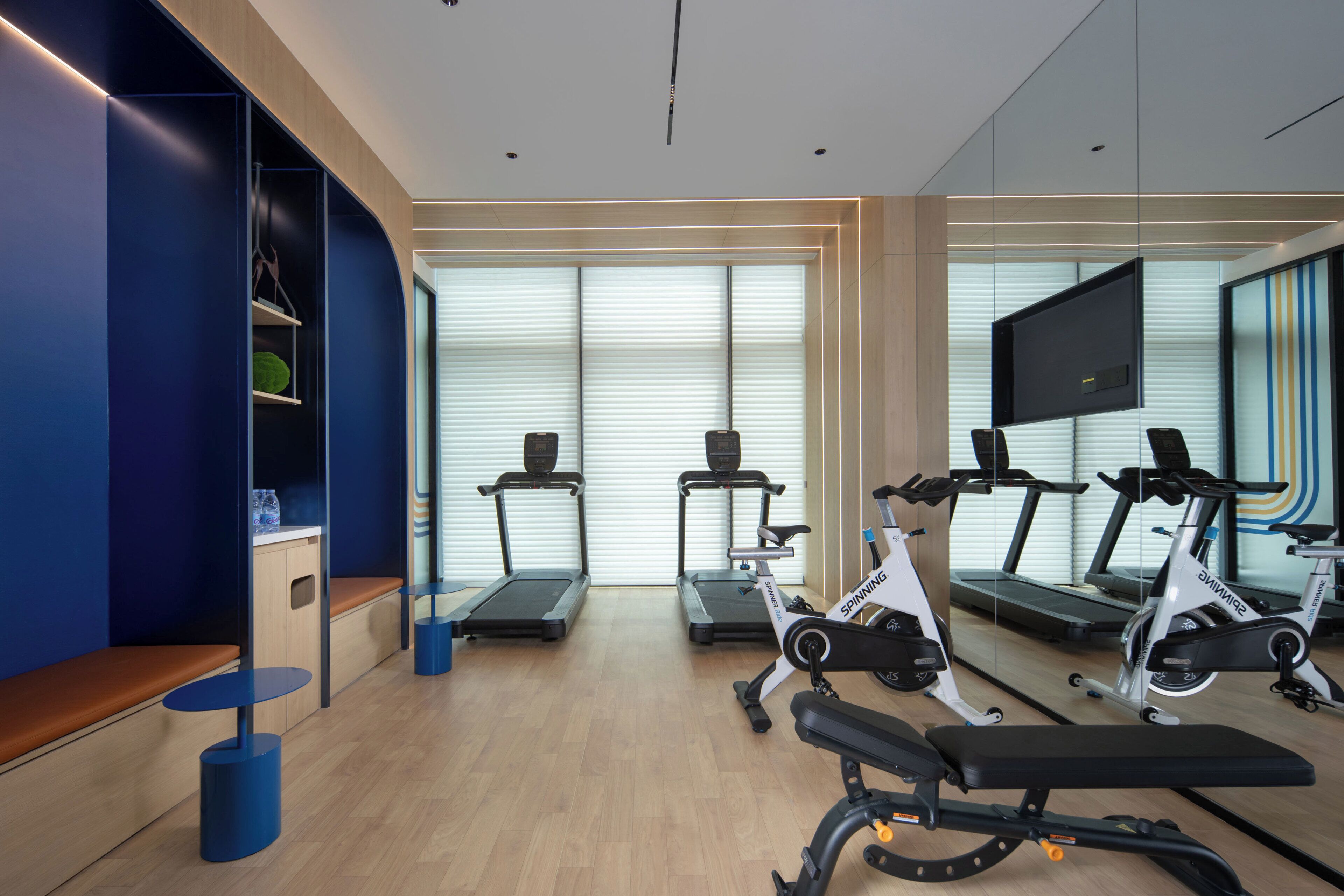 Un gimnasio moderno con equipo de ejercicio, zonas de descanso y amplias ventanas.