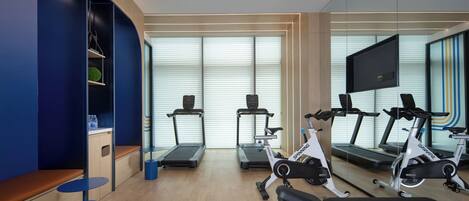 Un gimnasio moderno con equipo de ejercicio, zonas de descanso y amplias ventanas.